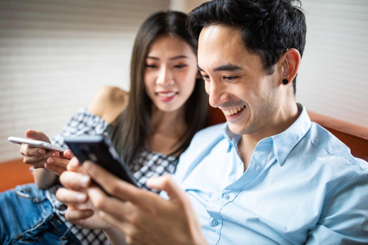 Man with a hearing aid looks at his phone.