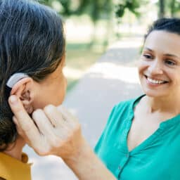 Woman with a hearing aid talking with her friend outdoors.