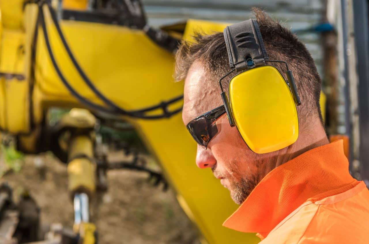 Man on a construction site wearing earmuffs to protect his hearing.